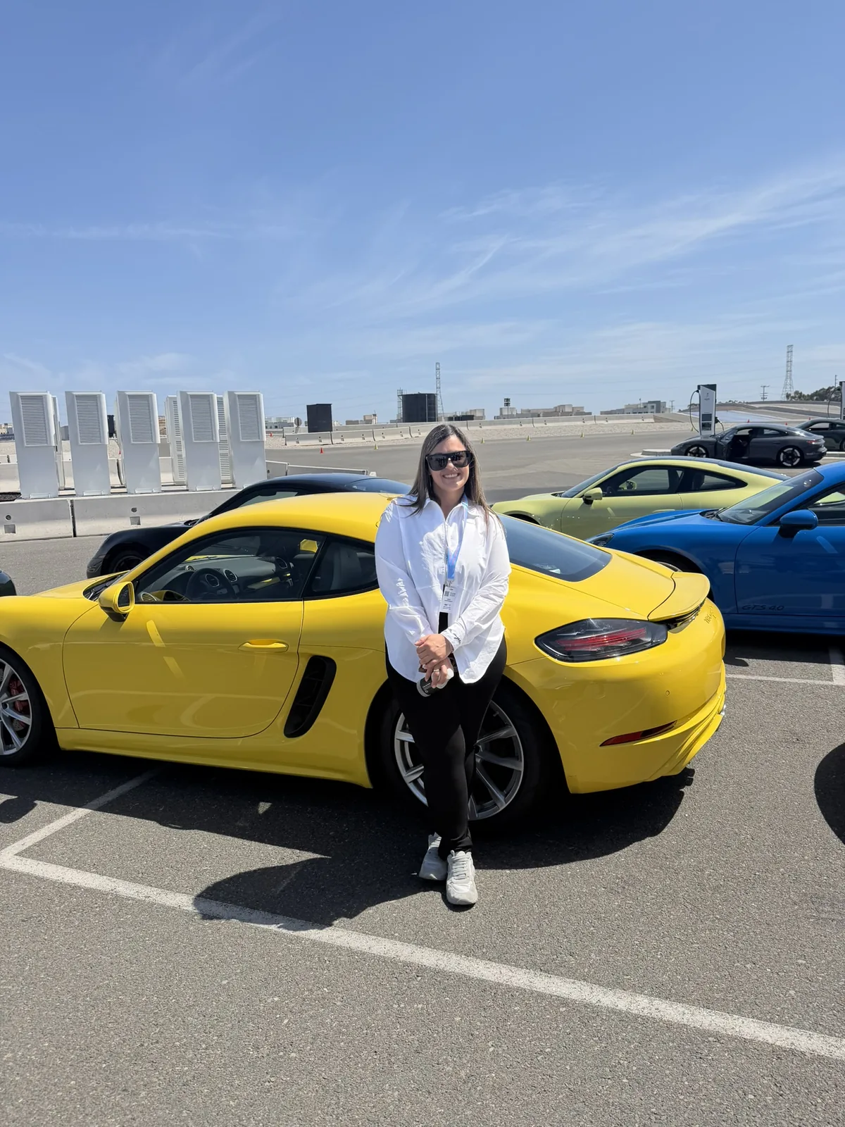 Dr. Andi-Jean Miro beside a yellow Porsche at Porsche Experience Center Los Angeles during IGNITE 2026