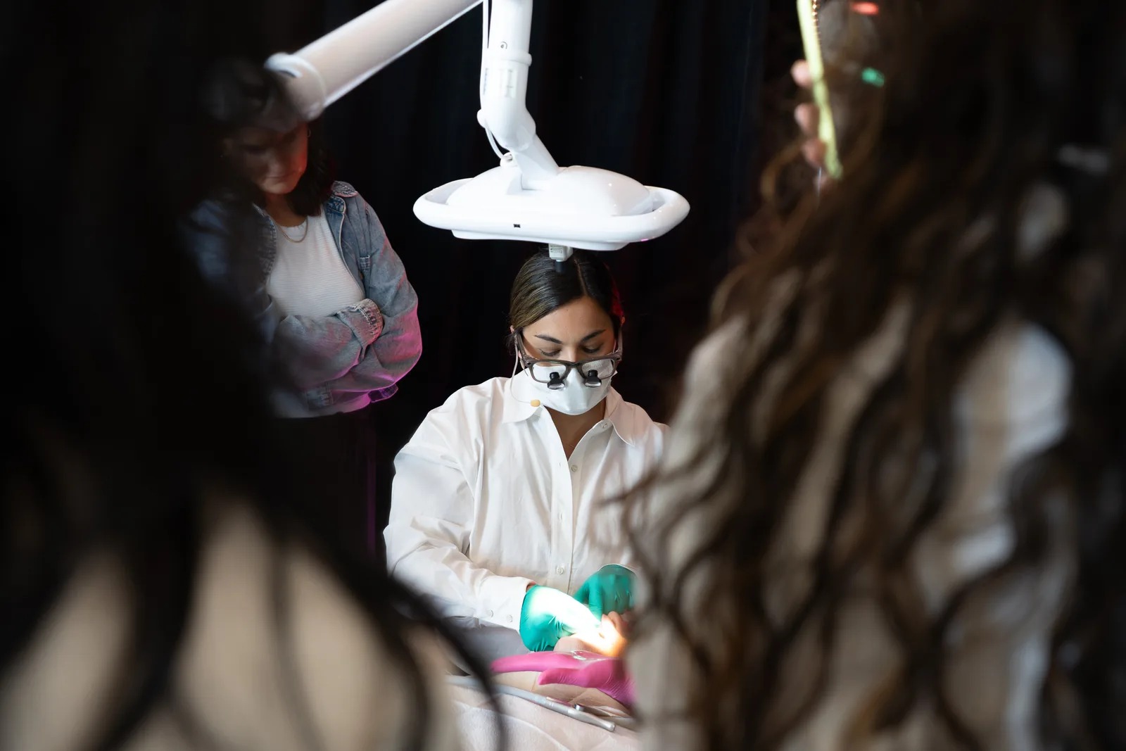 Attendees gathered around a clinician in loupes at the treatment chair at IGNITE 2026