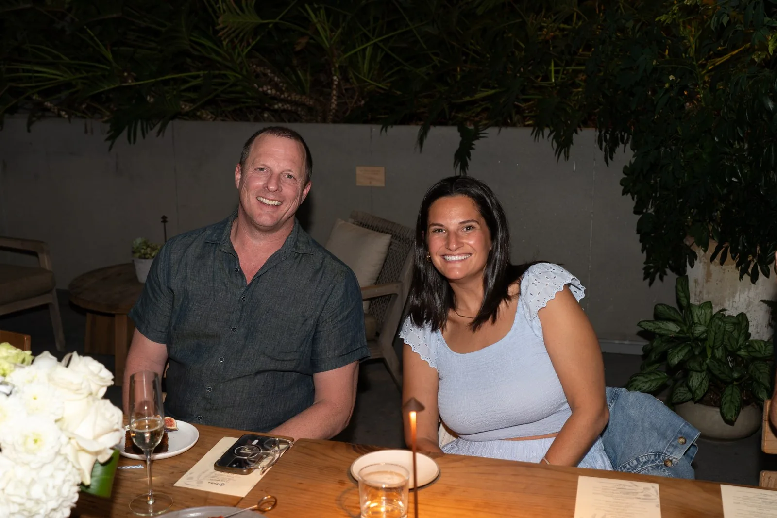 Two IGNITE 2026 guests at the candlelit table behind white florals