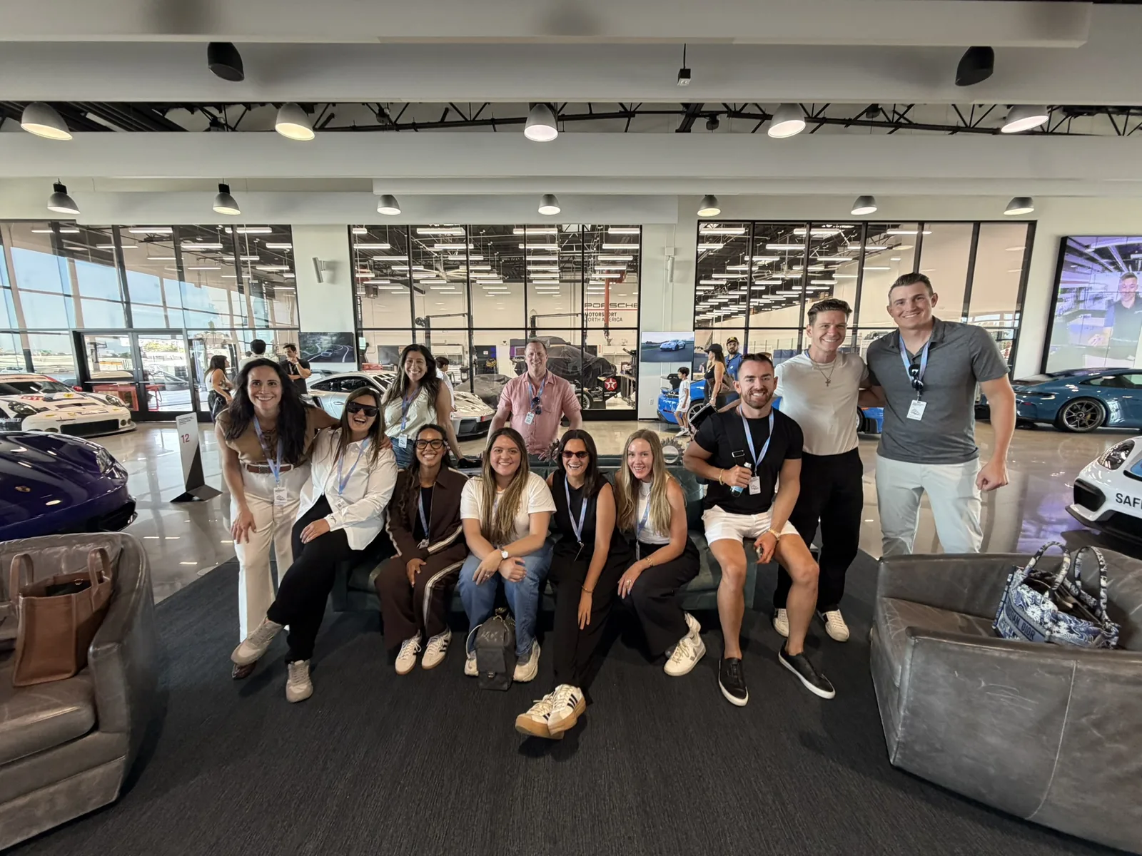 IGNITE 2026 attendees together in the Porsche Experience Center Los Angeles lounge, Porsches behind them
