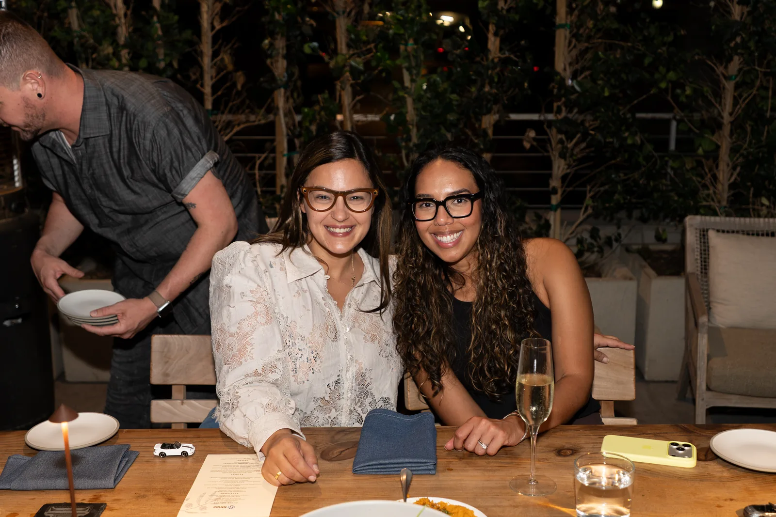 Two IGNITE 2026 guests smiling at the dinner table as plates are served
