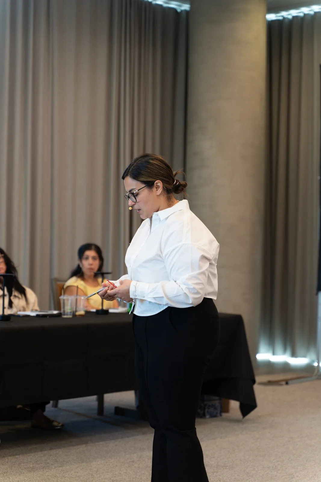 Presenter in a white blouse mid-explanation, the group behind, at IGNITE 2026