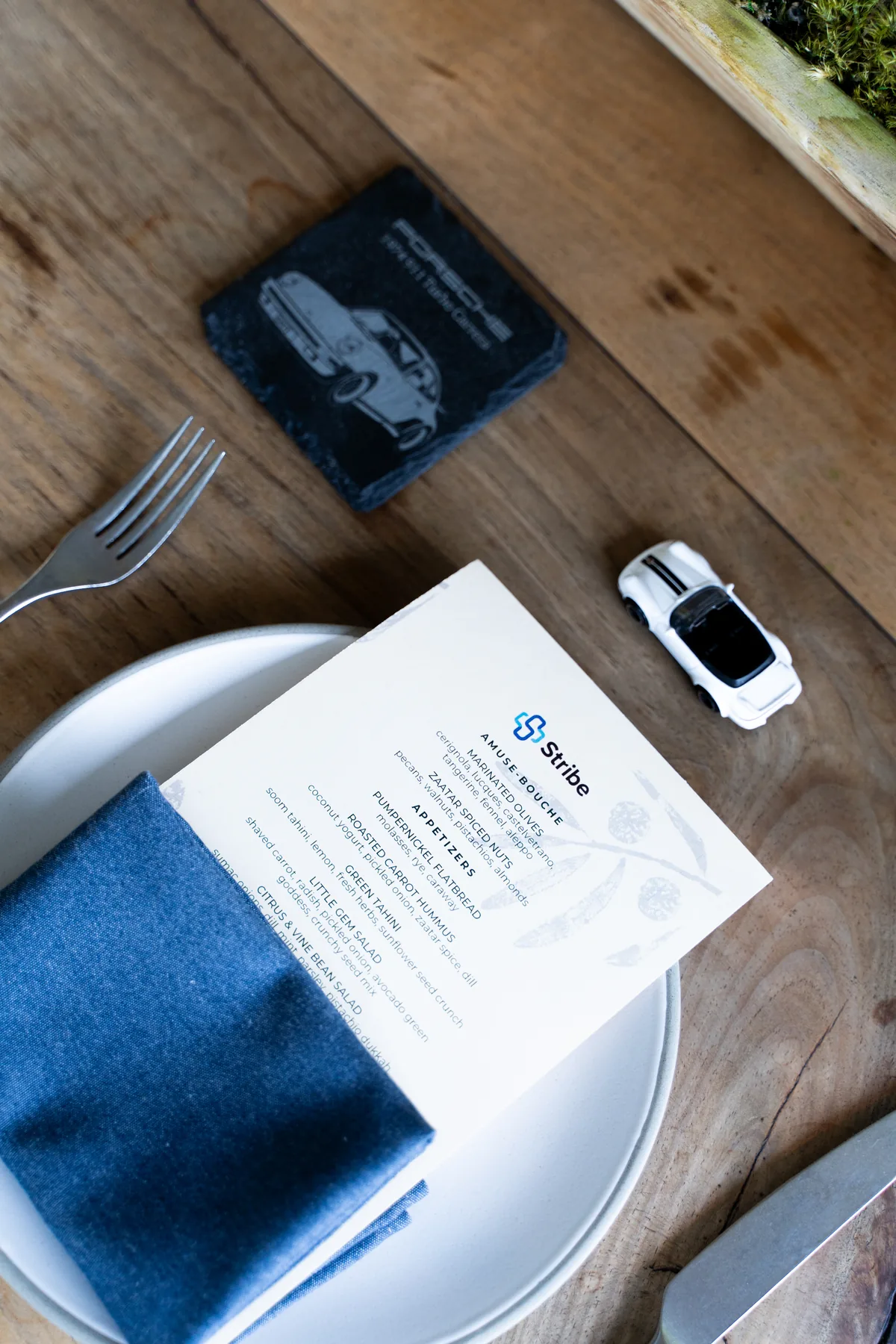 Stribe menu, engraved Porsche coaster and toy Porsche at an IGNITE 2026 place setting